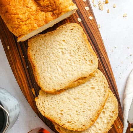 Three slices of bread machine buttermilk oat bread next to the loaf.