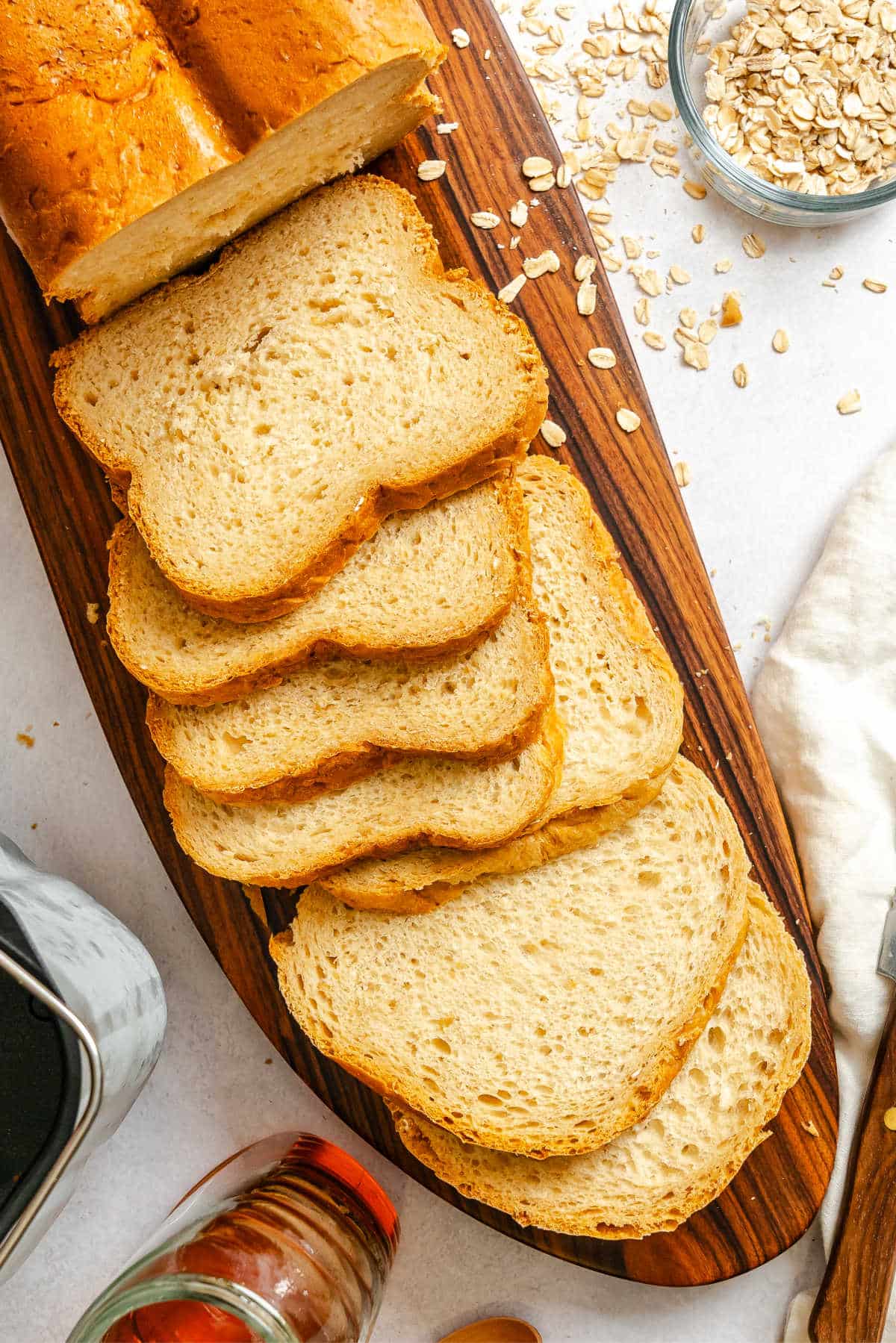 Slices of bread machine buttermilk oat bread on a wooden cutting board. 