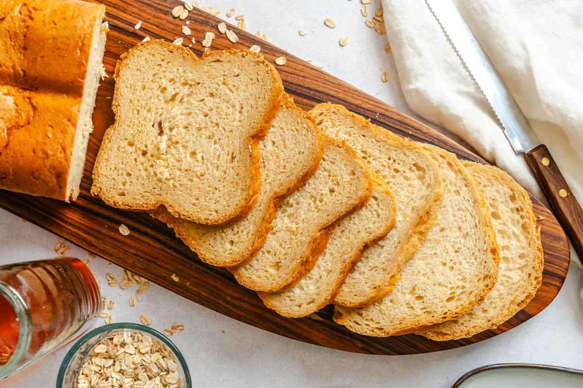 Slices of bread machine buttermilk oat bread next to a dish of oats. 