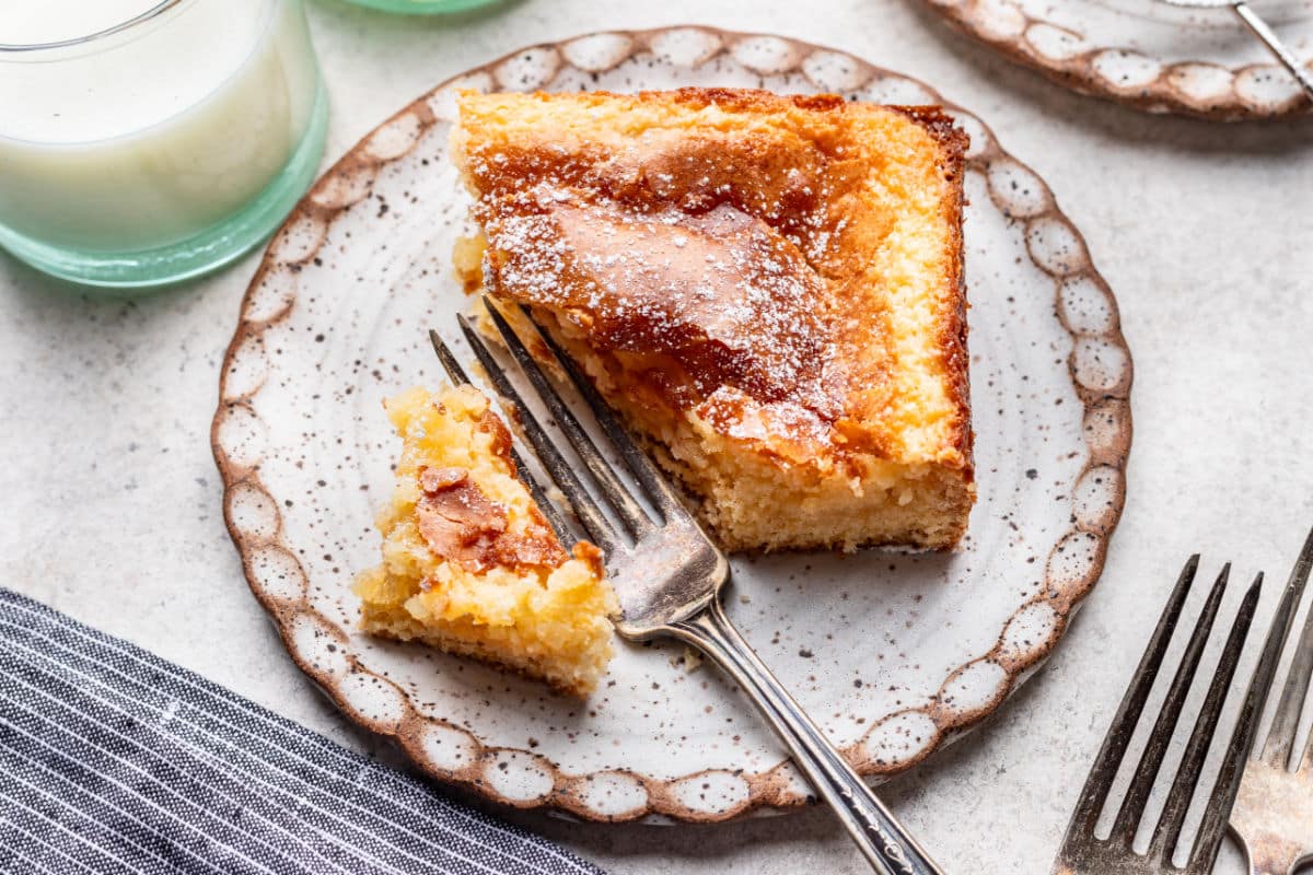 A fork taking a bite of gooey butter cake on a plate. 
