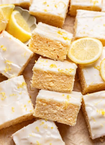 Three lemon brownies on their sides next to a half sliced lemon.