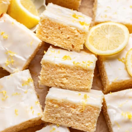 Three lemon brownies on their sides next to a half sliced lemon.