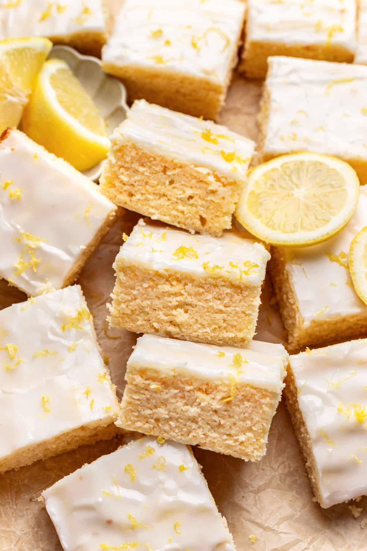 Three lemon brownies on their sides next to a half sliced lemon.