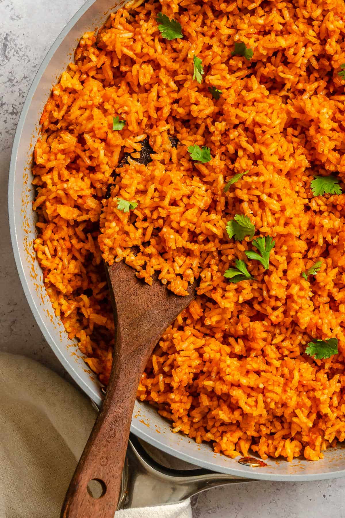 A wooden spoon holding a scoop of Mexican rice with cilantro on top. 
