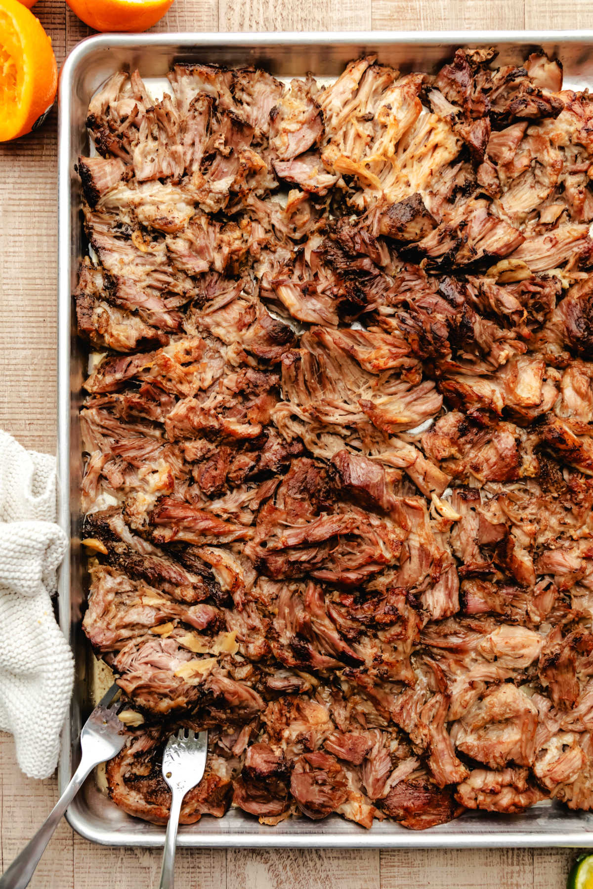 A tray of pork carnitas with two forks in it.