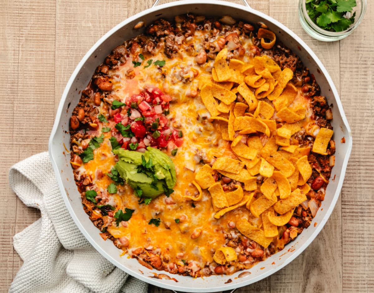 A taco skillet next to a dish of cilantro and a kitchen linen.