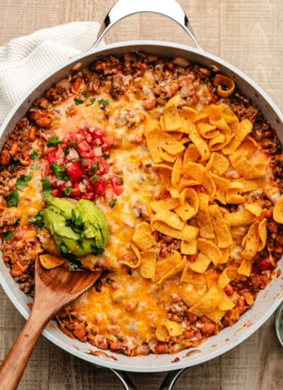 A taco skillet topped with corn chips, pico de gallo, and guac.
