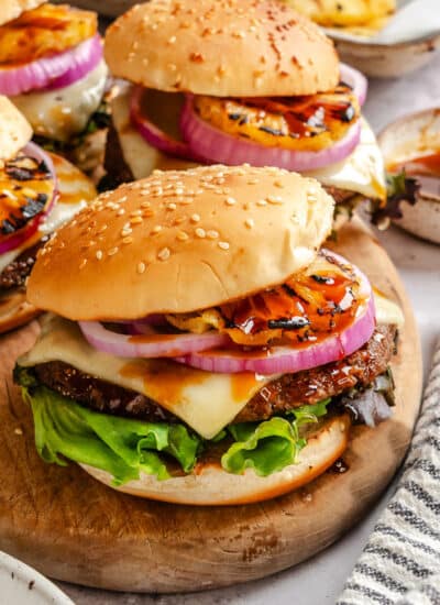 Aloha burgers sitting on a wooden cutting board.