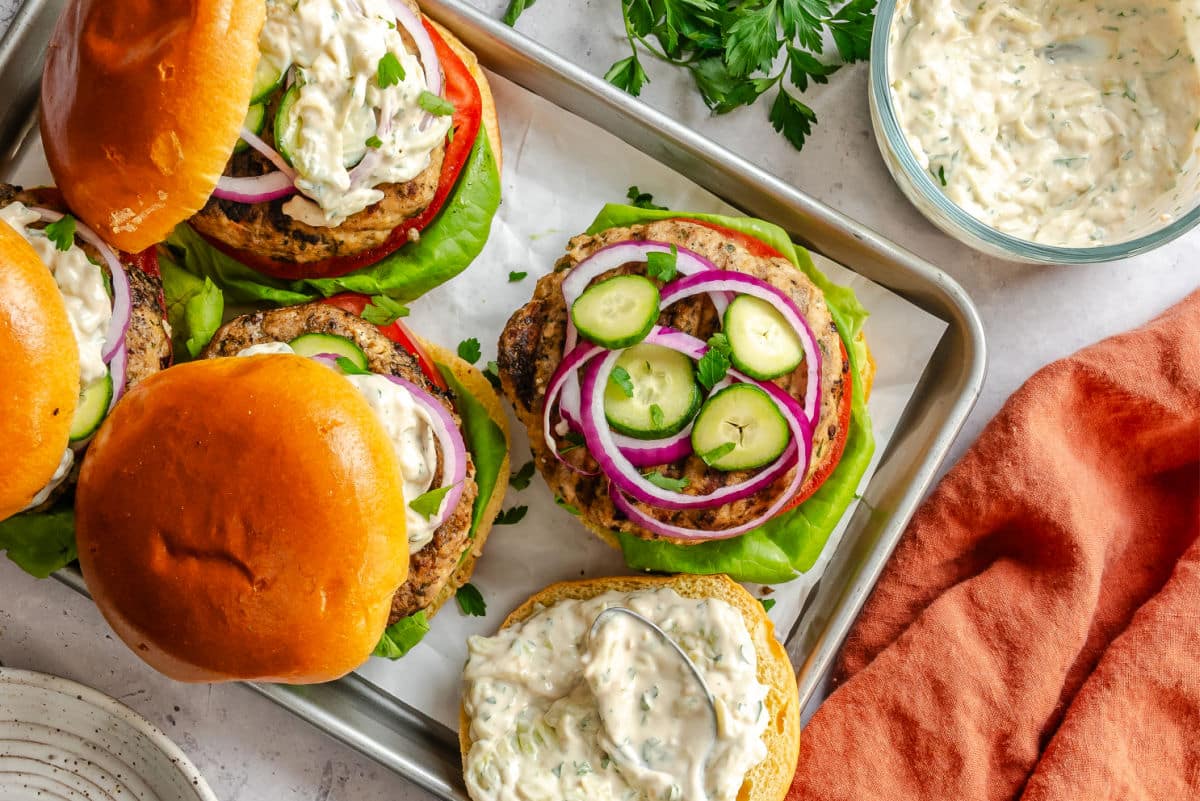 A tray of Greek turkey burgers next to a bowl of  tzatziki. 