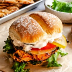 A grilled chicken sandwich on a piece of brown parchment paper.