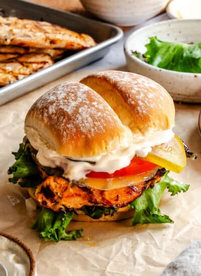 A grilled chicken sandwich on a piece of brown parchment paper.