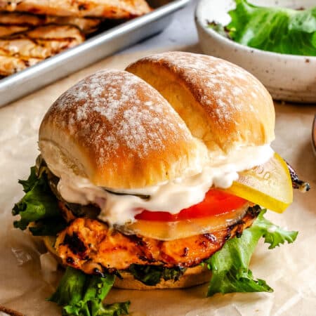 A grilled chicken sandwich on a piece of brown parchment paper.