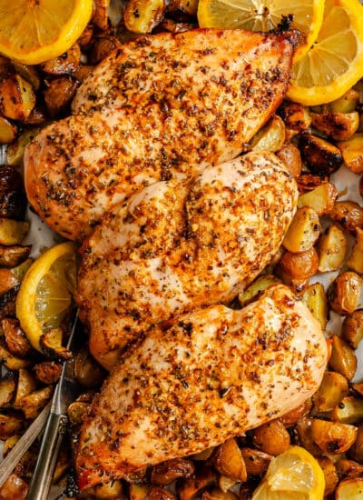 Three lemon garlic chicken breasts on roast potatoes.