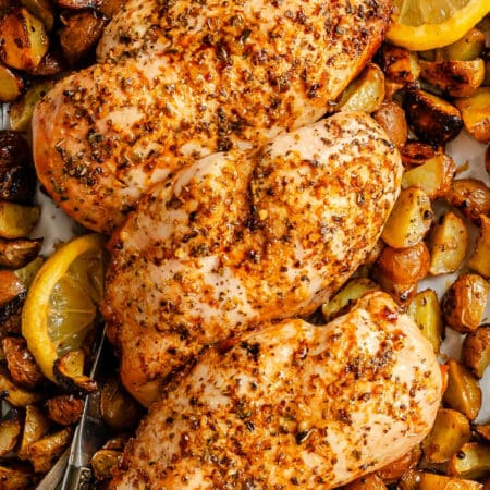 Three lemon garlic chicken breasts on roast potatoes.