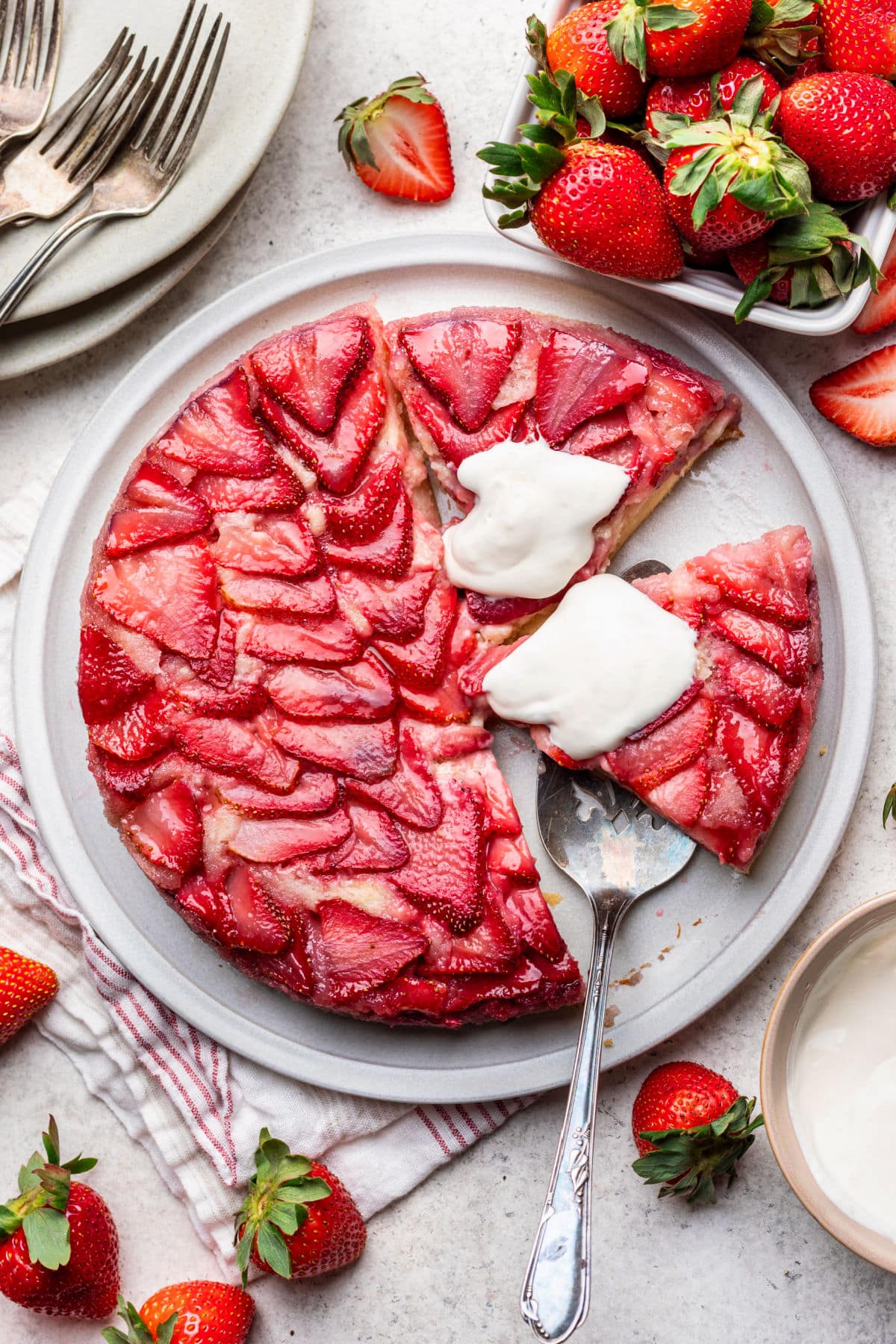 Two cut slices of strawberry upside down cake topped with whipped cream on a plate. 