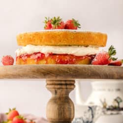 A Victoria sponge cake on a wooden cake stand.