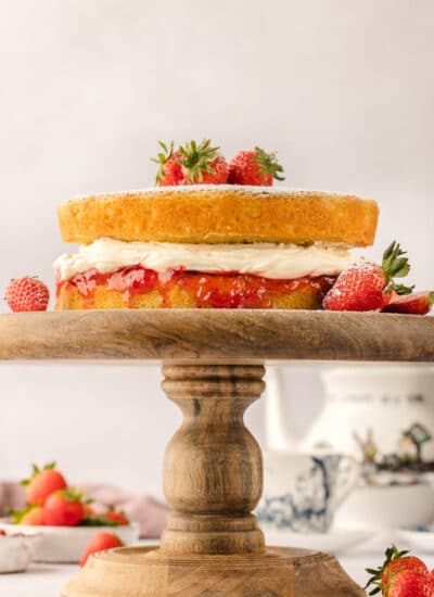 A Victoria sponge cake on a wooden cake stand.