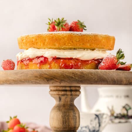 A Victoria sponge cake on a wooden cake stand.