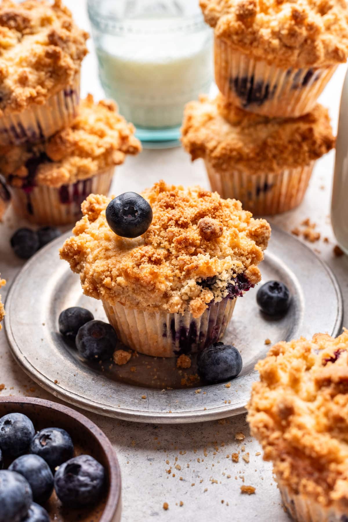 A blueberry streusel muffin with a blueberry on top of it on a plate.