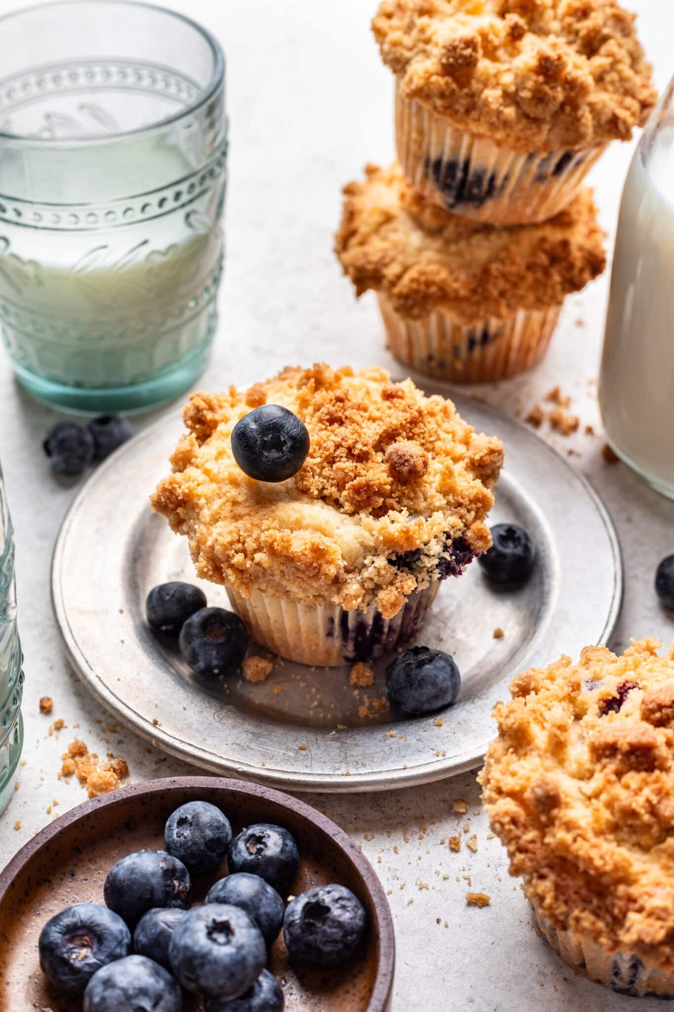 A blueberry muffin next to two stacked blueberry muffins.
