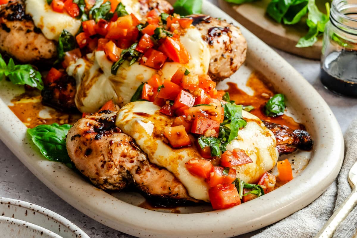 A piece of grilled bruschetta chicken topped with fresh basil and bruschetta topping.