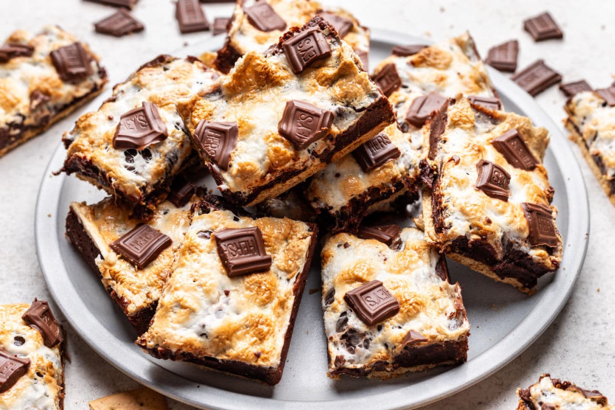 A plate of s'mores brownies surrounded by pieces of broken chocolate. 