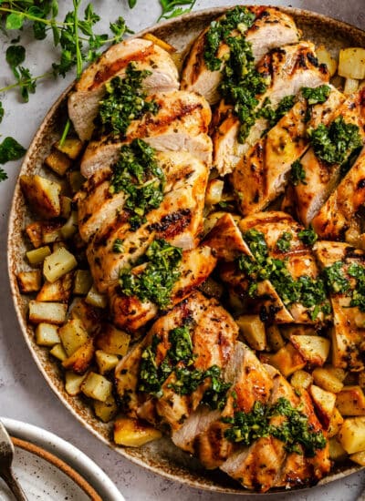 Sliced of grilled chimichurri chicken over roast potatoes.