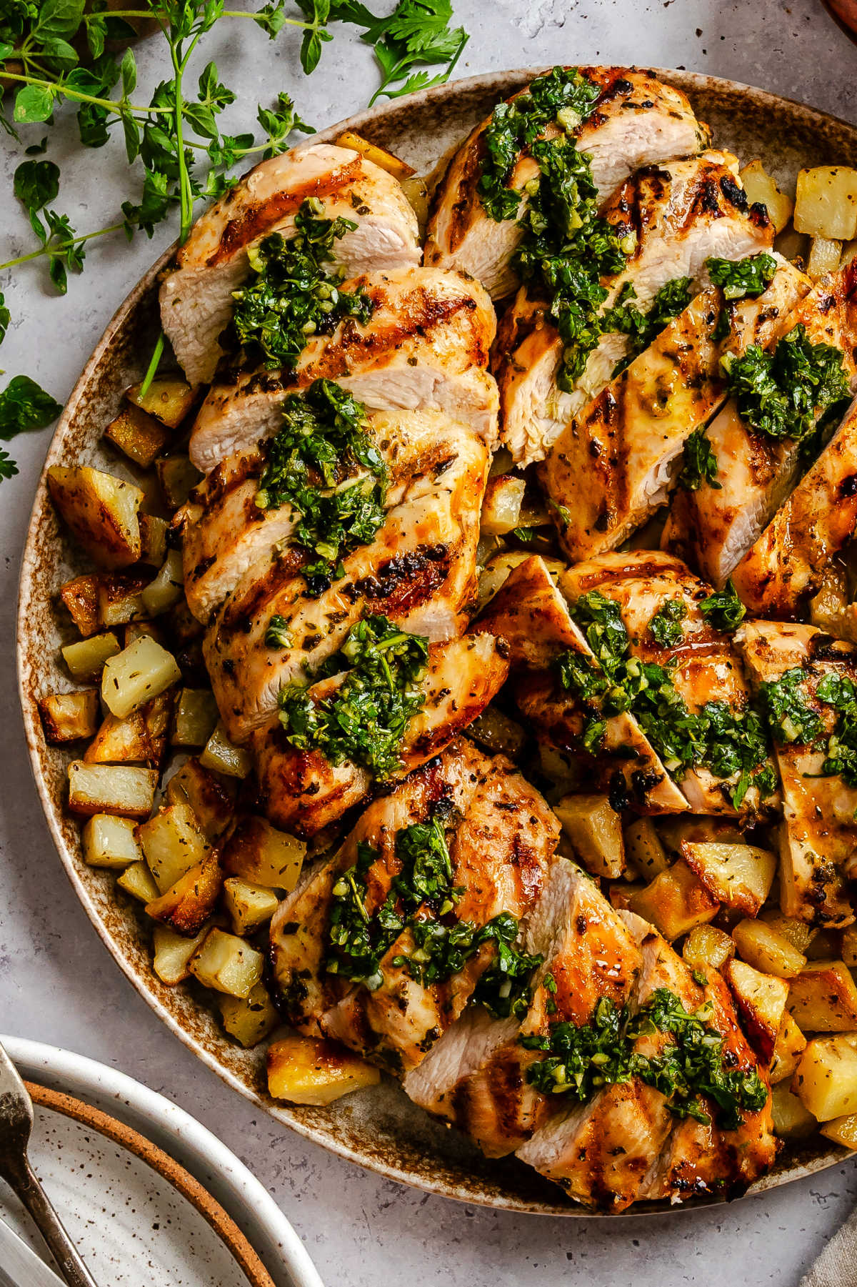 Sliced of grilled chimichurri chicken over roast potatoes.