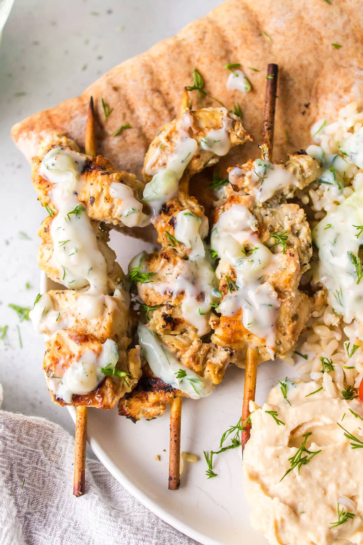 Grilled Greek chicken skewers topped with tzatziki.