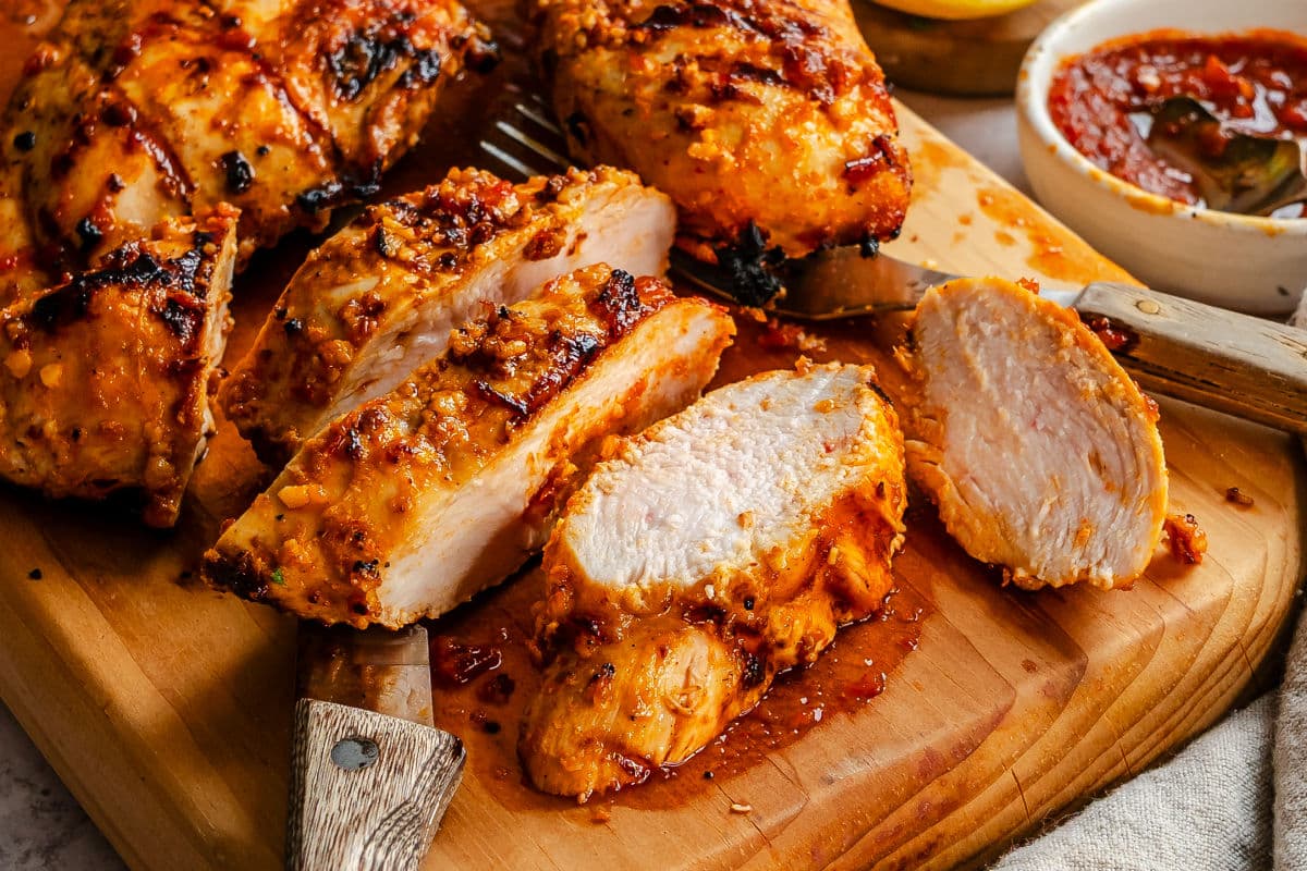 Harissa chicken on a wooden cutting board.