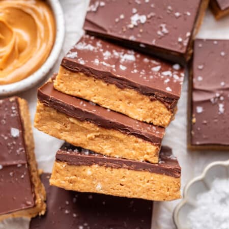Three no bake peanut butter bars sideways overlapping more bars.