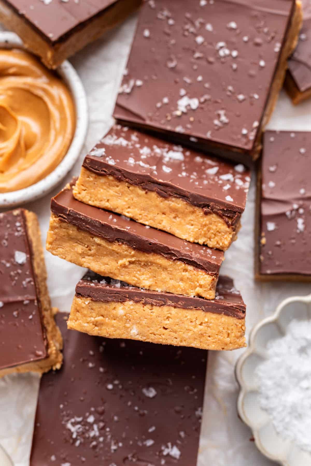 Three no bake peanut butter bars sideways overlapping more bars.