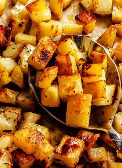 A spoon holding a scoop of roast potatoes.