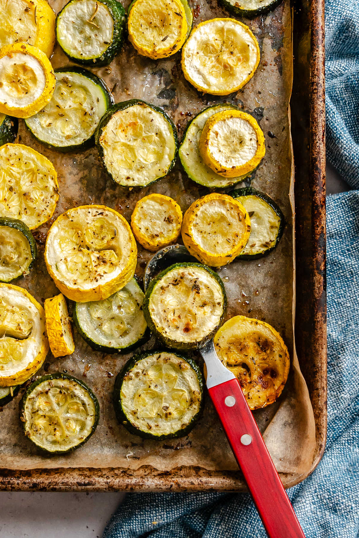 A sheet pan with a spatula holding a scoop of roast squash and zucchini.