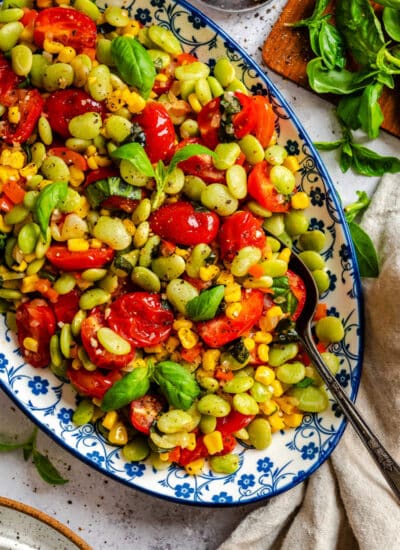 A dish of summer succotash with a serving spoon in it.