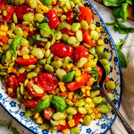 A dish of summer succotash with a serving spoon in it.