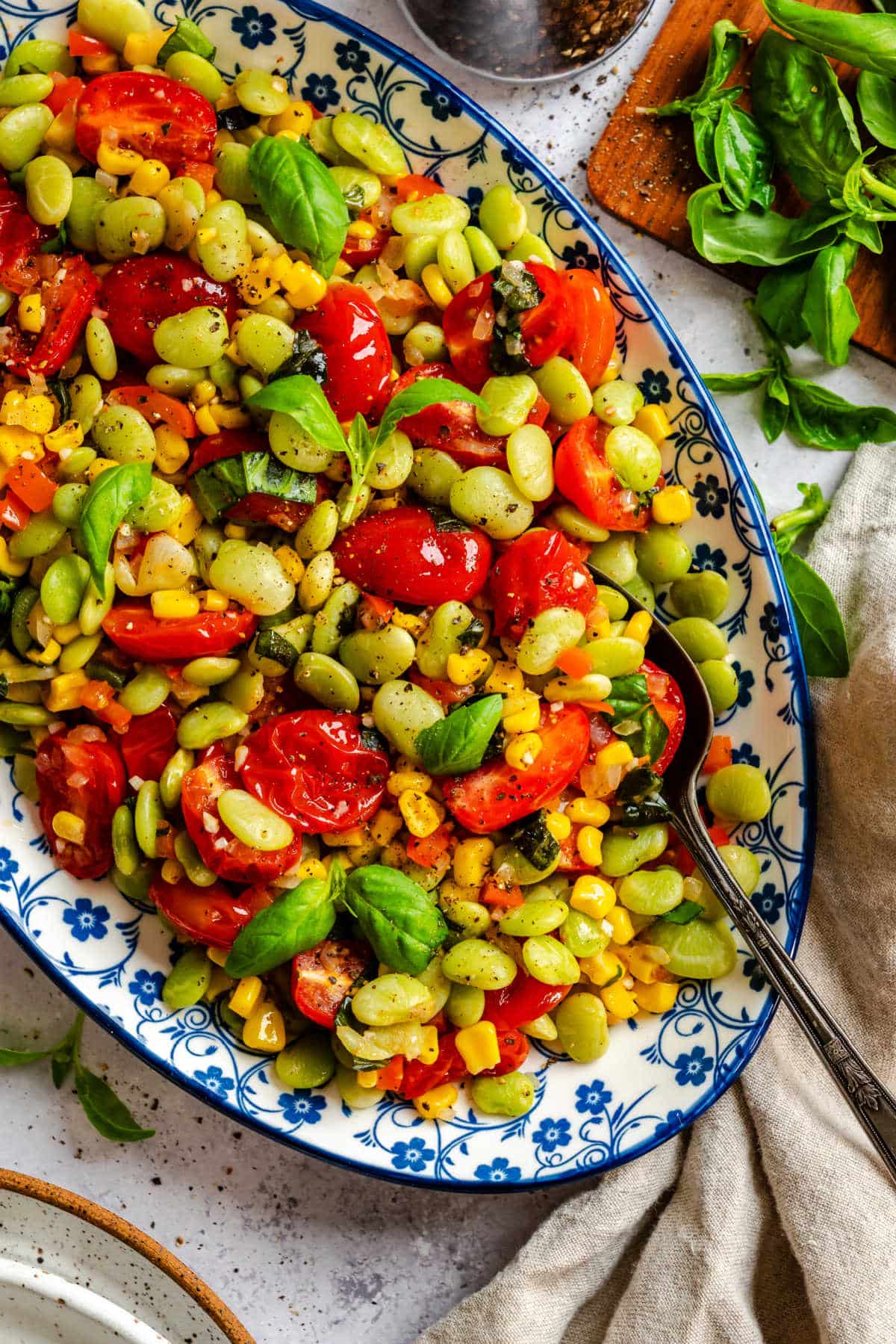 A dish of summer succotash with a serving spoon in it.