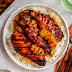 A plate of grilled huli huli chicken and pineapple on rice.