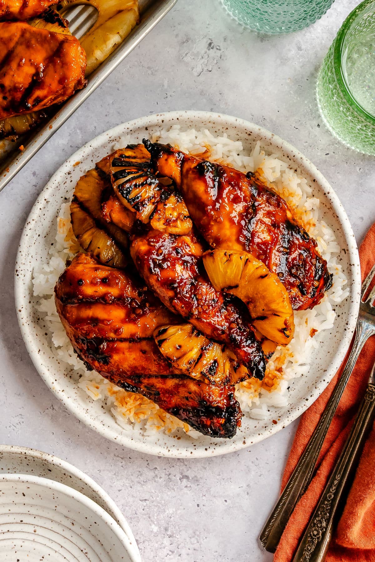 A plate of grilled huli huli chicken and pineapple on rice.
