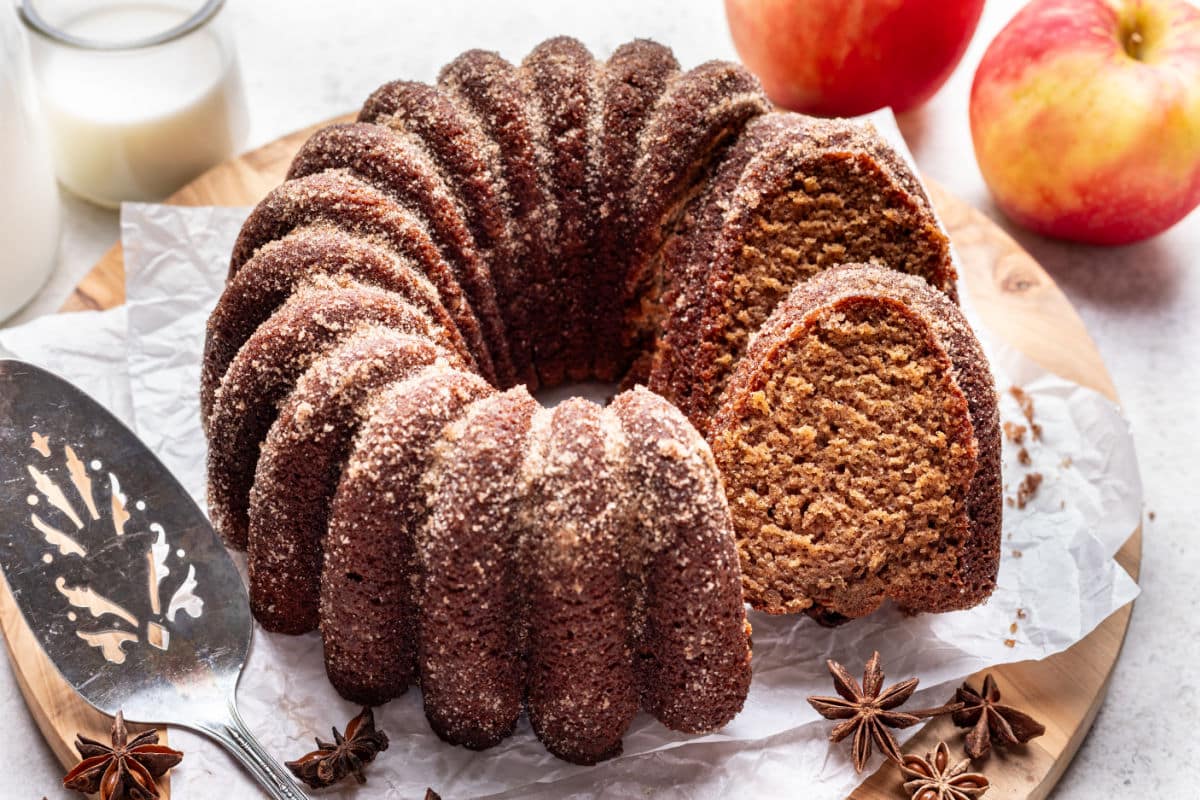 A slice of apple cider bundt cake leaning against the cake.