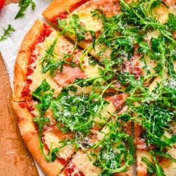 A pizza topped with prosciutto and agrugula.