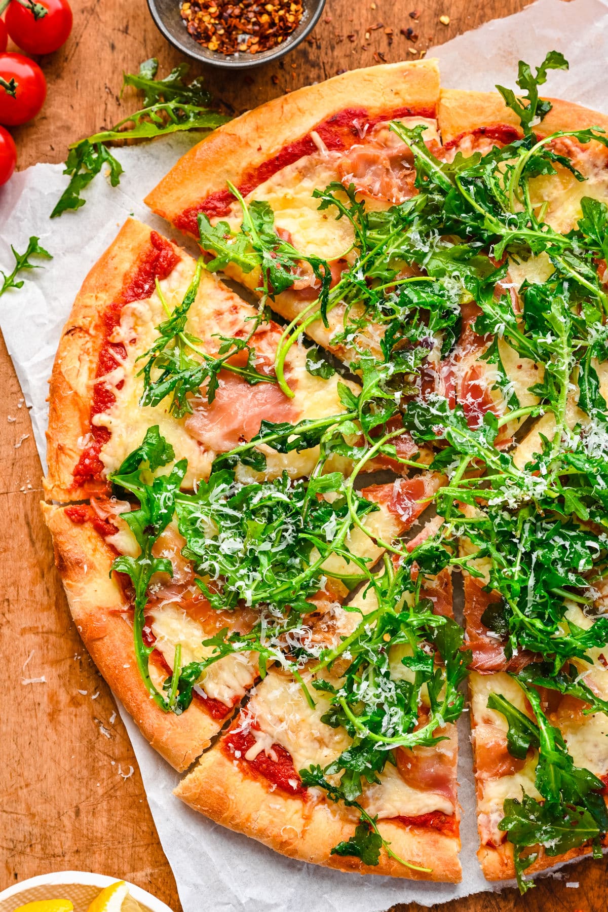 A pizza topped with prosciutto and agrugula.