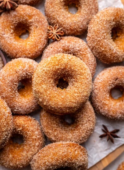 Overlapping baked pumpkin donuts coated with cinnamon sugar.
