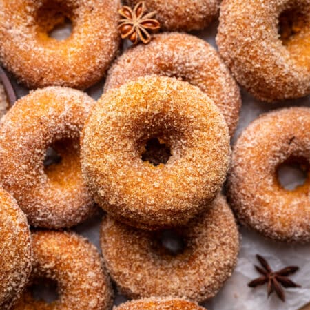 Overlapping baked pumpkin donuts coated with cinnamon sugar.