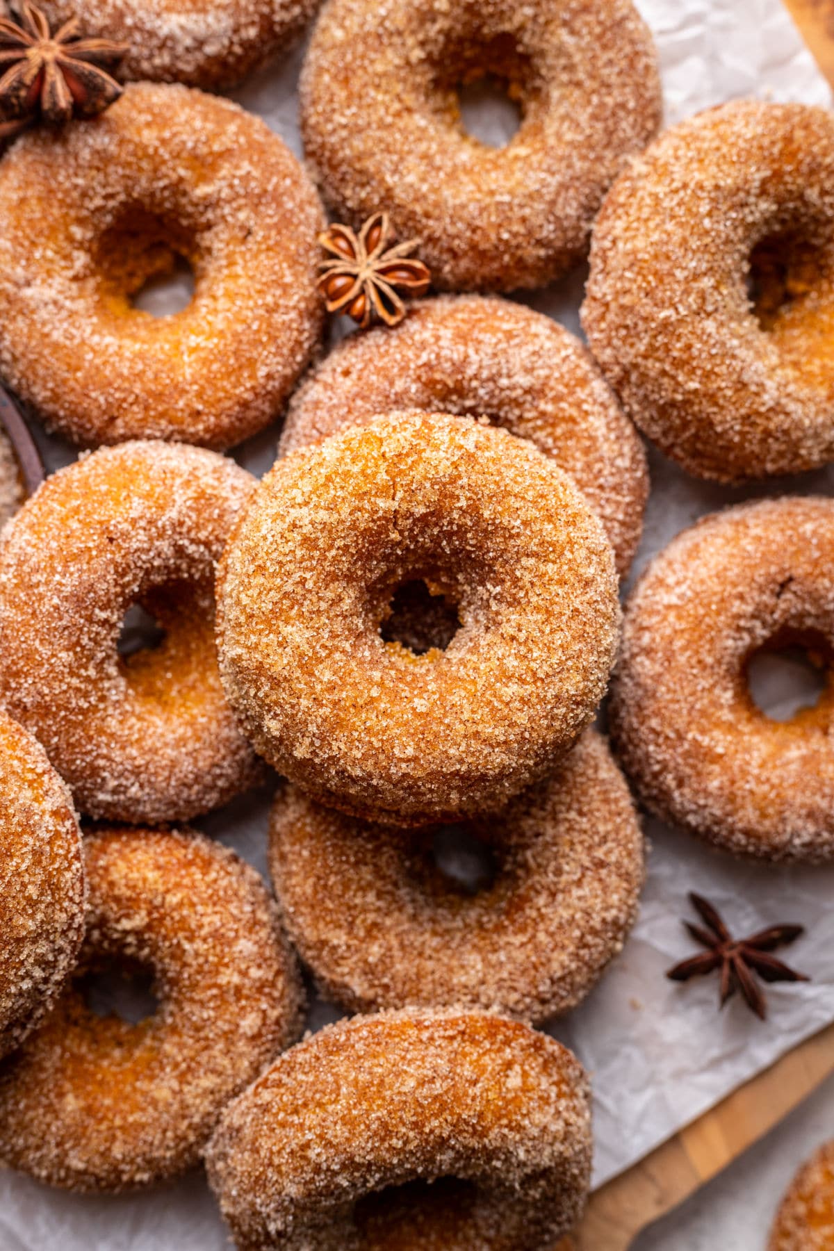 Overlapping baked pumpkin donuts coated with cinnamon sugar.