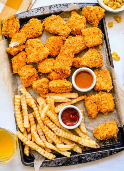 Baked chicken nuggets and fries on a baking sheet.