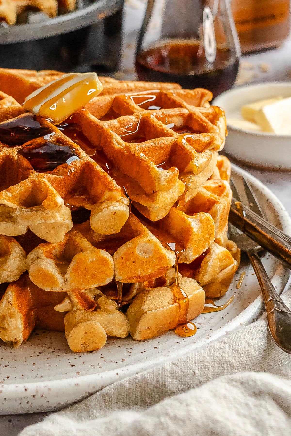 A stack of cottage cheese waffles topped with butter and syrup.
