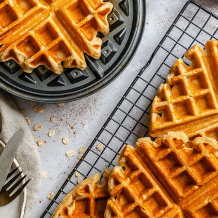 Cottage cheese waffles overlapping next to the waffle on the waffle iron.