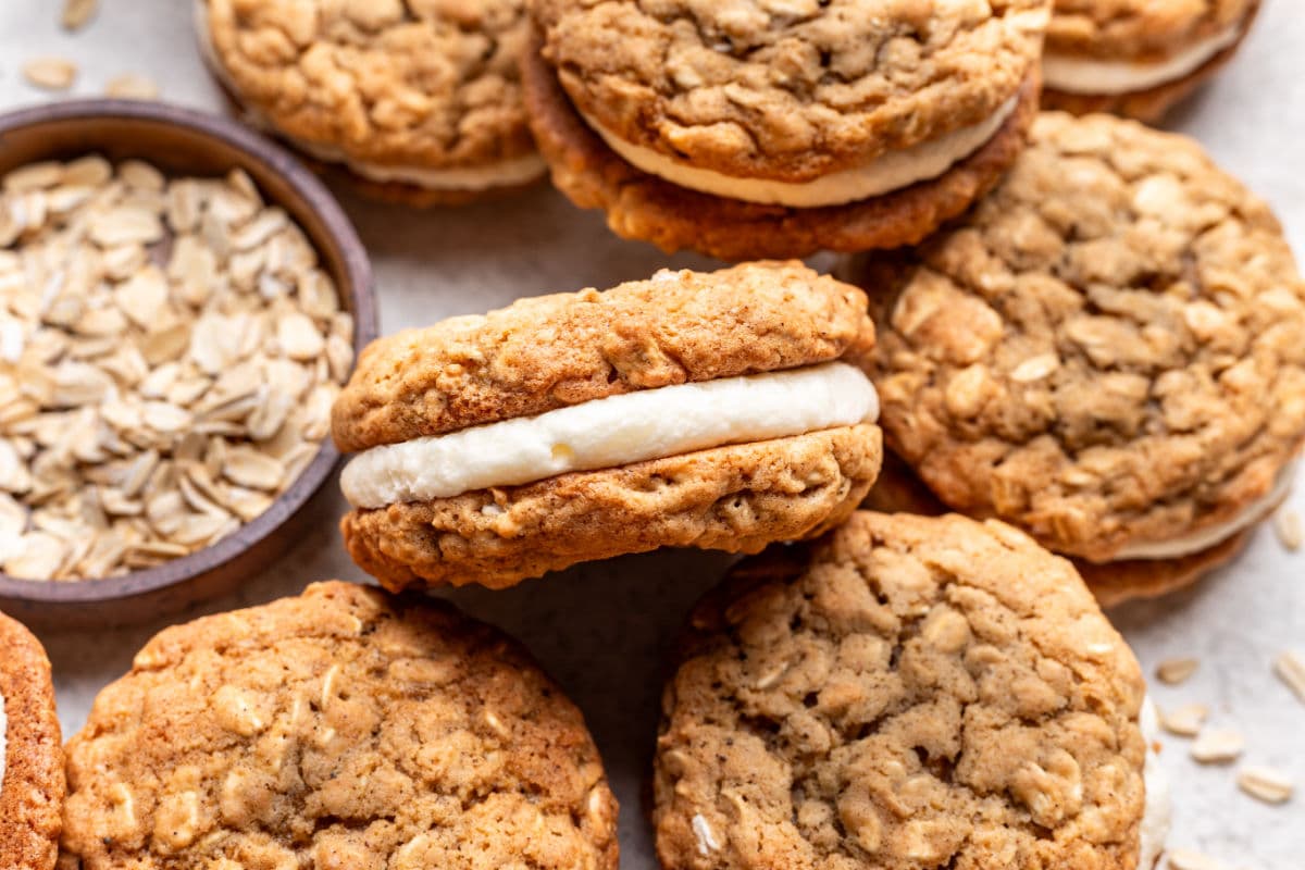 Overlapping oatmeal cream pies next to a dish of oats.