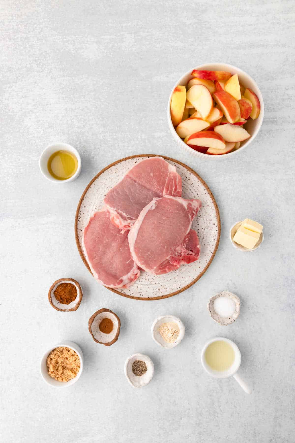 Ingredients for pork chops and apples in dishes.